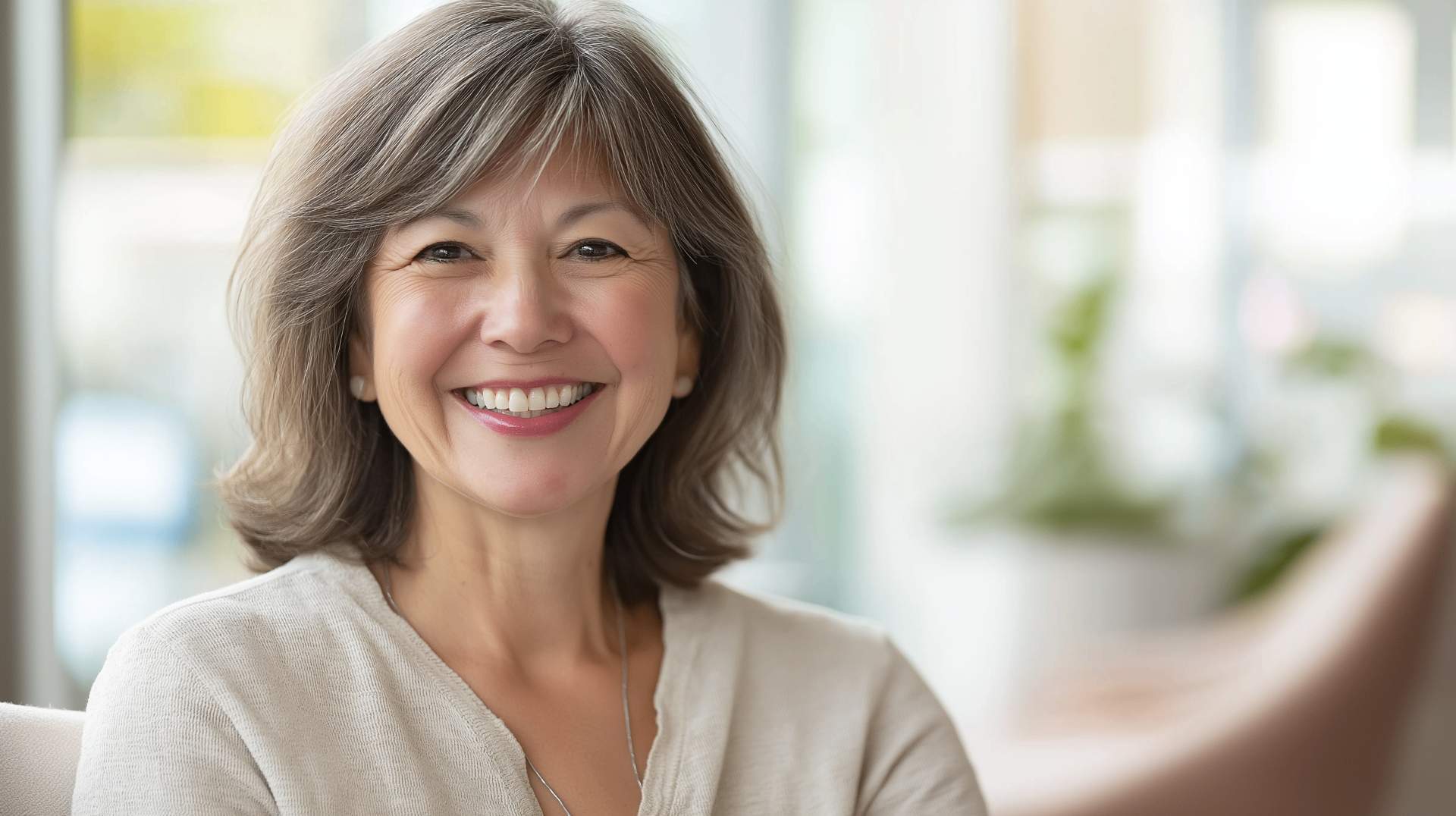 Senior woman smiling confidently showing healthy teeth in a bright, modern dental office